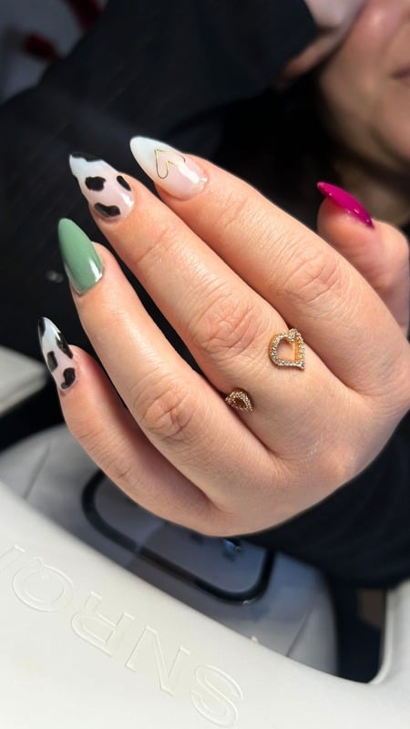 Diseño de uñas almendra con arte cow print y verde sage